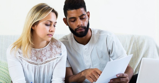 couple looking distressed looking at bills