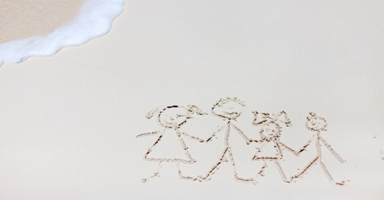 stick figure family drawn in the sand at the beach