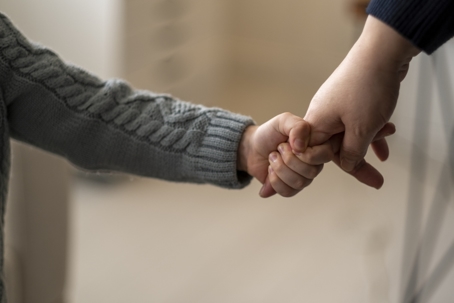 small child holding onto parent's finger
