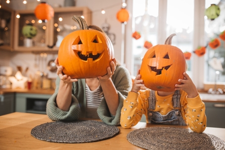 parent and child playing with carved pumpkins